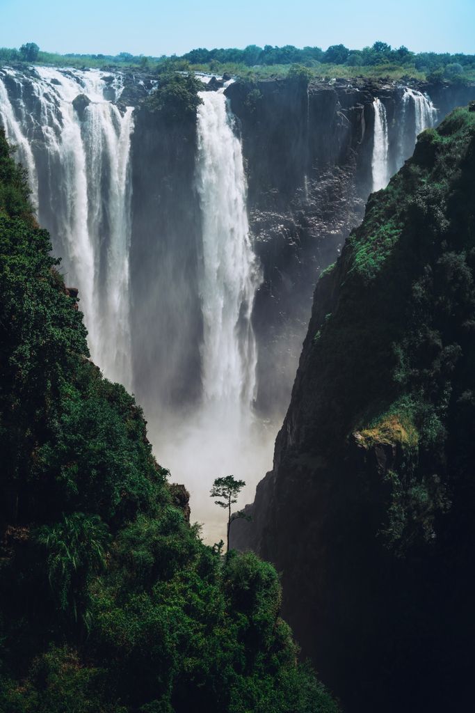Stunning view of Victoria Falls with cascading water and lush greenery in the background.